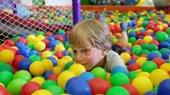 可爱的蹒跚学步的男孩孩子在儿童操场上玩五颜六色的球在室内视频的预览图