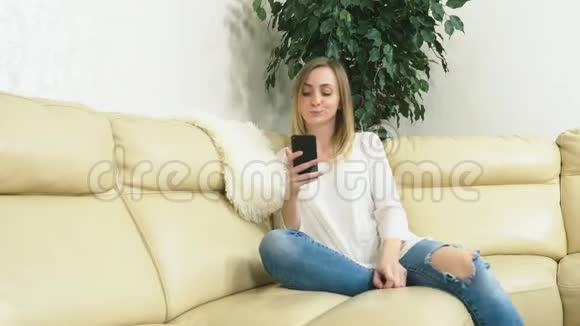 心烦意乱的女孩在家里坐在沙发上用智能手机坏消息视频的预览图