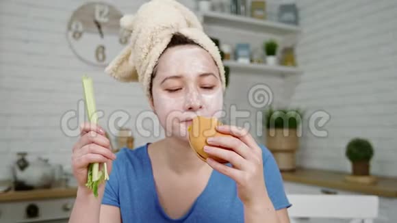 带着面具的女孩开心地在厨房吃汉堡包视频的预览图