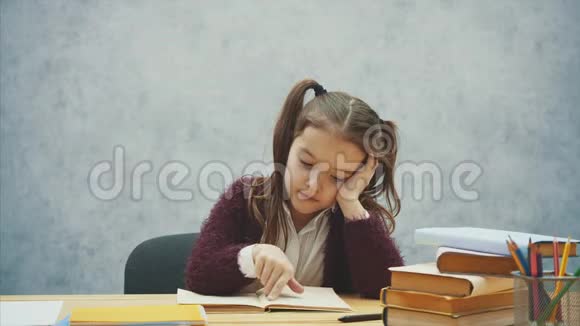 小女孩读一本书坐在灰色的内部学习教科书的女学生穿校服的孩子视频的预览图