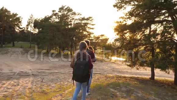 女孩们带着背包穿过树林徒步旅行者女孩一家人在树林里散步女孩旅行穿过森林视频的预览图
