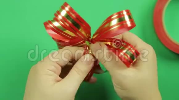 女人双手伸直红丝带礼物蝴蝶结的花瓣并给它形状绿色背景视频的预览图