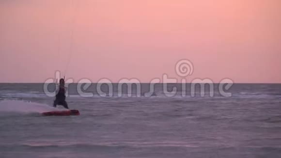 这名男子控制着一只训练风筝背景是日落慢镜头拍摄视频的预览图