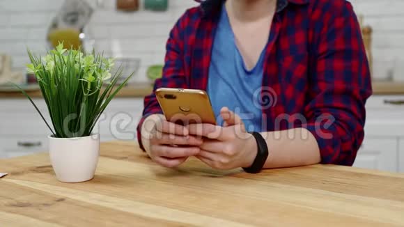 女人坐在厨房的桌子上在智能手机上发短信视频的预览图