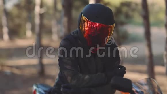 日落时戴黑色头盔的摩托车手的肖像森林中的自行车彩色面罩视频的预览图