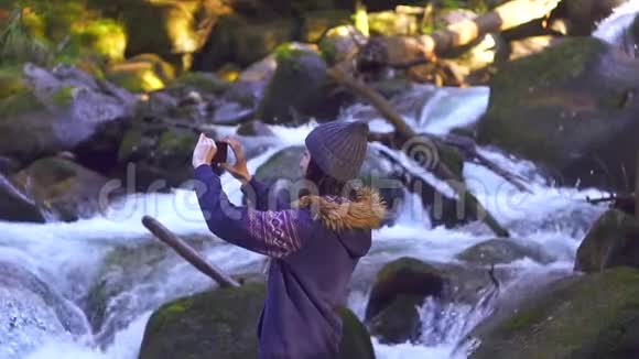 女孩在森林里给一条美丽的山河拍照慢悠悠的视频的预览图