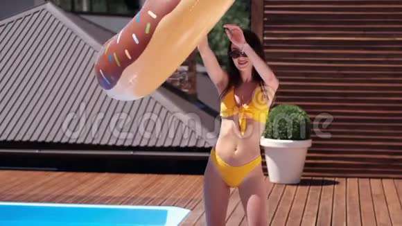 美丽的女孩穿着五颜六色的泳装美丽的身材玩着游泳池旁的充气玩具视频的预览图