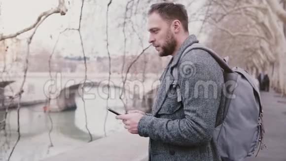 年轻快乐的男性旅行者带着背包在罗马的提伯河岸拍照享受寒假视频的预览图