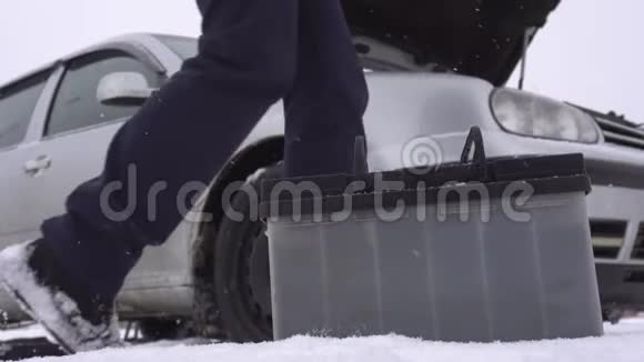 冬天汽车背景上的电池被放电司机在汽车附近行走启动时出现问题视频的预览图