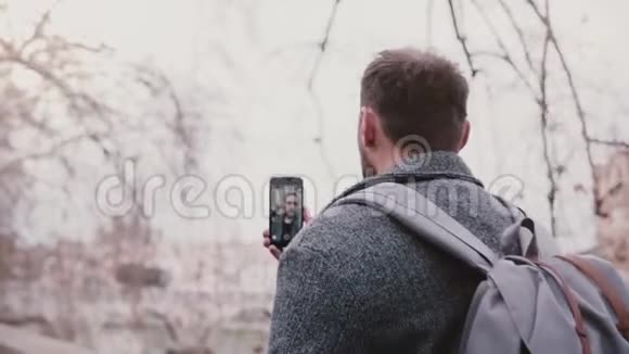年轻成功的高加索视频博客作者在冬天的罗马街头散步时用智能手机拍摄自己视频的预览图