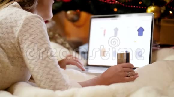特写4k镜头年轻女子在圣诞树下的笔记本电脑上做网上购物购买圣诞礼物及视频的预览图
