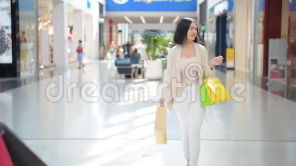 两个带着购物袋在室内散步的女孩在购物中心拥抱对方视频的预览图