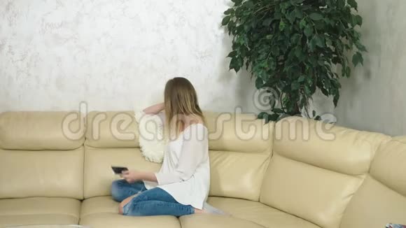 心烦意乱的女孩在家里坐在沙发上用智能手机坏消息视频的预览图