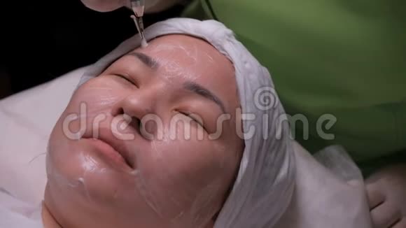 一个亚洲女孩在美容办公室里不受信任的程序女性面部的电流清洁视频的预览图