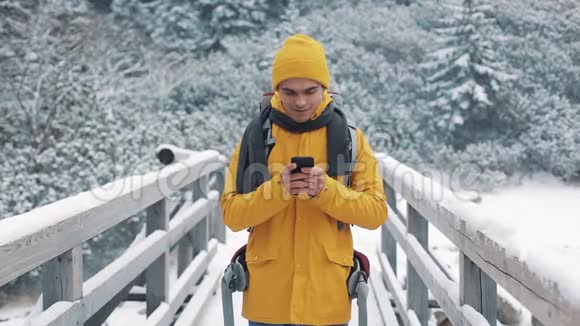 一位年轻的游客站在桥上使用智能手机Hiker看着手机庆祝好消息视频的预览图
