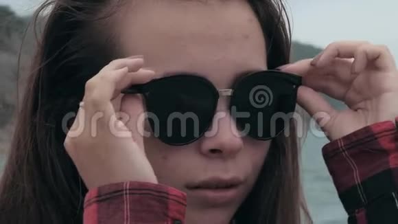 热带海滩上美丽的年轻的欧洲女孩戴太阳镜的特写肖像背景是大海女孩视频的预览图