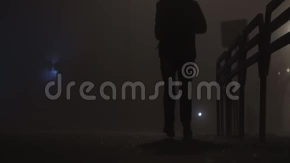 穿着夹克的男性在夜间在雾中或雾中慢跑视频的预览图