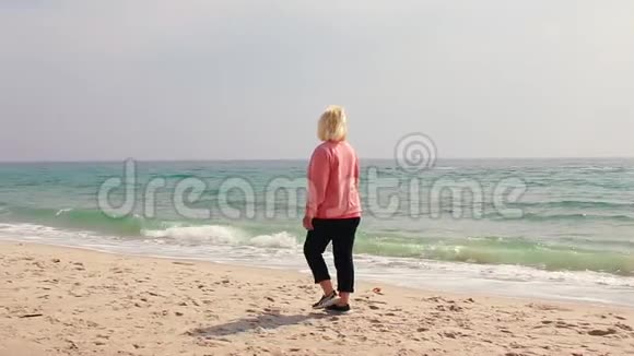 成年妇女在海边的沙滩上散步视频的预览图