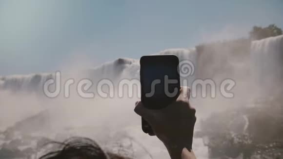 慢动作特写人手握大智能手机拍摄不可思议的尼亚加拉瀑布全景视频的预览图