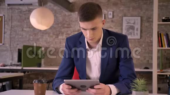 年轻的严肃商人正在看平板电脑喝咖啡交流观念商业观念视频的预览图