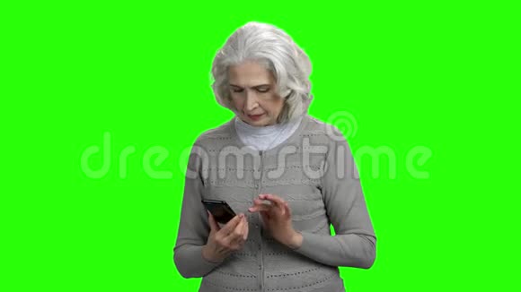 微笑的高级妇女与智能手机在绿色屏幕上视频的预览图