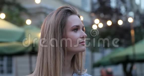 一个相当浪漫的女孩的肖像向旁边看把她的脸转向相机夜晚的城市灯火通明视频的预览图