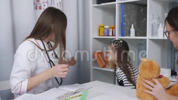 一位女医生为一个小女孩病人检查喉咙痛妈妈和小女儿在招待会上视频的预览图