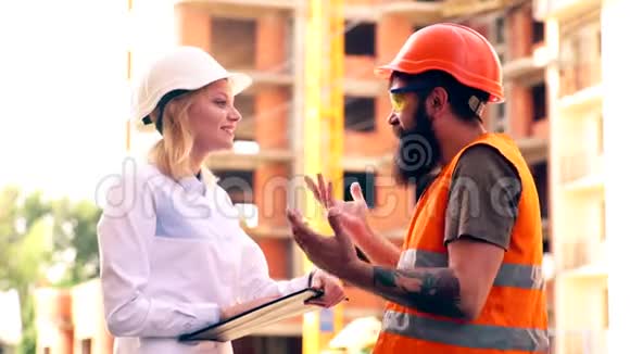 施工负责人与施工现场工人讨论工作细节戴着白色头盔的女人视频的预览图