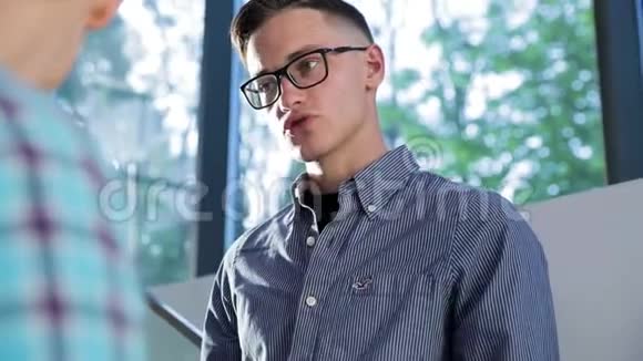 戴眼镜的年轻人在光办公室说话的画像视频的预览图