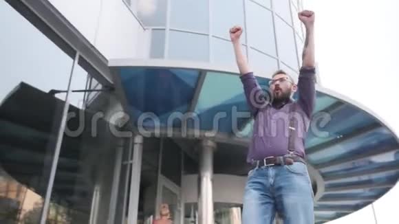 一个男人很兴奋他走路跳尖叫和举起双手反对高楼大厦视频的预览图