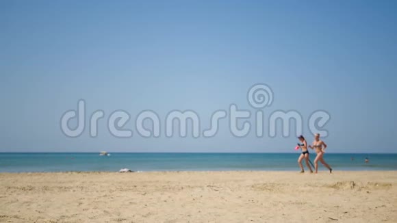 两个年轻的女朋友穿着泳装沿着海岸跑不受相机的关注休闲和旅游的概念视频的预览图