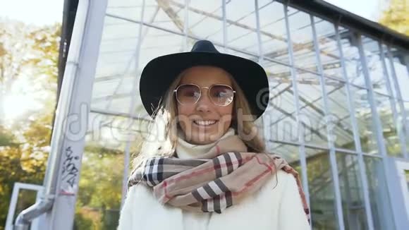 在城市公园里一位戴着帽子的时髦金发女人对着镜头微笑视频的预览图