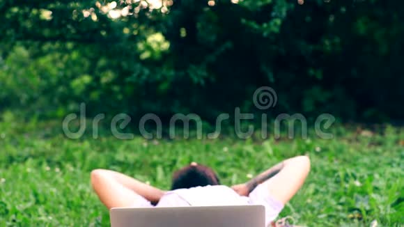 那个留胡子的人坐在公园的草地上用笔记本电脑工作理念的产生学生是视频的预览图