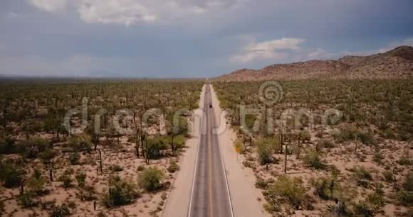 无人机在美丽的沙漠道路上飞行汽车在美国亚利桑那州国家公园的大大气仙人掌田视频的预览图
