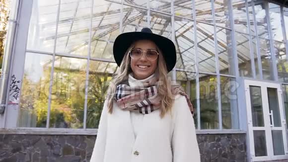 肖像拍摄年轻漂亮的女人戴着太阳镜看着相机在公园的背景上微笑视频的预览图