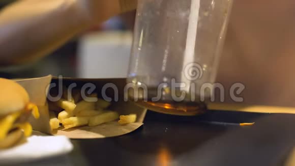 自助餐顾客通过塑料吸管喝苏打水桌上有炸薯条视频的预览图