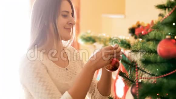 一幅美丽的笑脸女人在客厅装饰圣诞树的画像上面挂着五颜六色的花苞和珠子视频的预览图