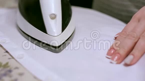 家庭主妇用电熨斗熨白色T恤视频的预览图