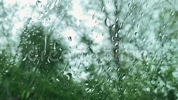 多云背景的窗户玻璃表面有雨滴在雨中开车从车窗上看到水滴视频的预览图