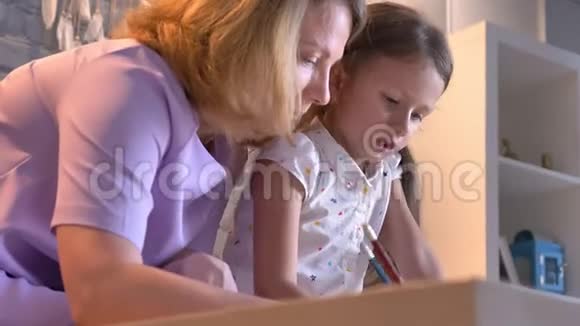 白种人的母亲和女儿一起做家庭作业帮助孩子学习坐在现代家庭家庭观念视频的预览图