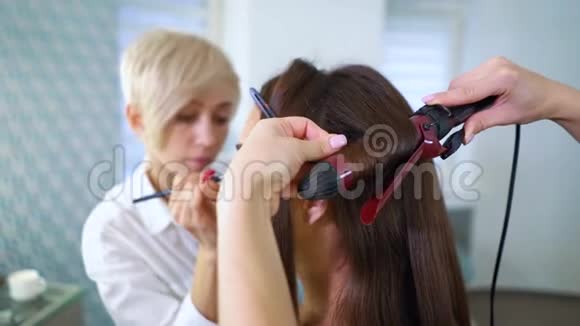 化妆师和理发师为可爱可爱的年轻女人化妆和发型视频的预览图