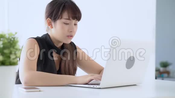 美丽的年轻自由职业亚洲女性微笑着工作在手提电脑和交谈客户电话视频的预览图