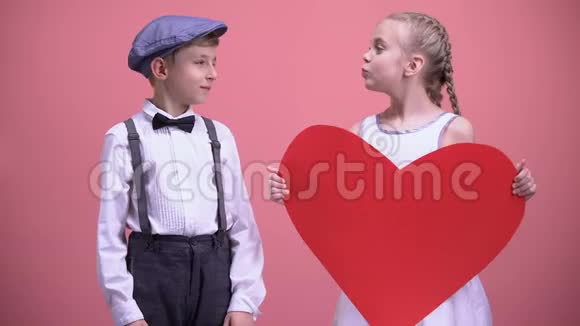 红纸心的小女孩试图亲吻小男孩男孩子退缩约会视频的预览图