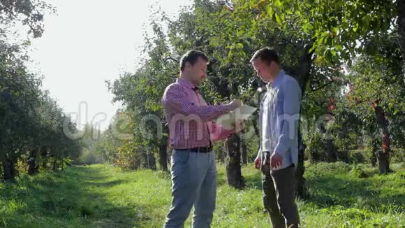 两个农民准备在苹果园达成协议视频的预览图