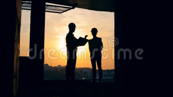 一名男性和一名女性工程师站在一栋多层建筑中的剪影建筑工地视频的预览图