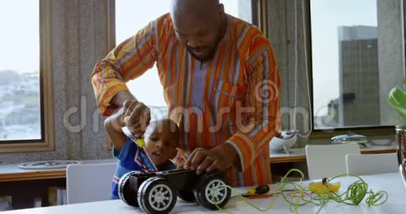 父子俩在舒适的家里修理玩具车视频的预览图