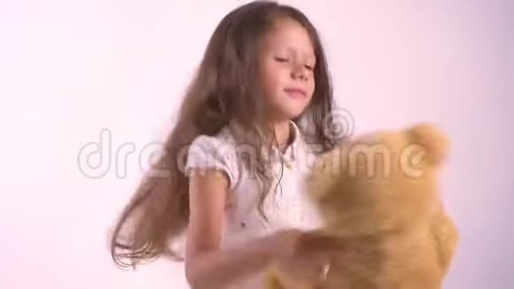 小男孩玩毛绒玩具熊和跳舞拿着玩具孤立地站在粉红色的工作室背景上视频的预览图