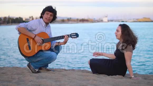 美丽的音乐家夫妇坐在海边的码头上视频的预览图