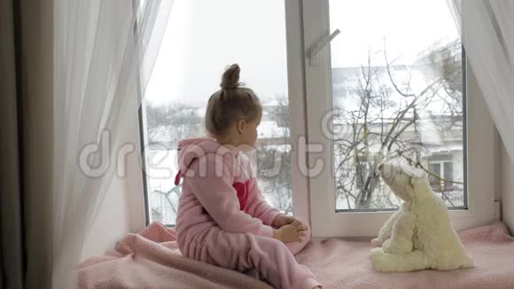 女孩拿着玩具坐在窗台上视频的预览图