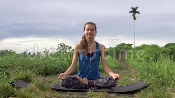 女人冥想瑜伽姿势听智能手机上的咒语视频的预览图